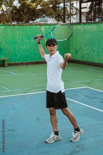 male tennis player preparing to hit the ball during serve when playing on the tennis court © Odua Images