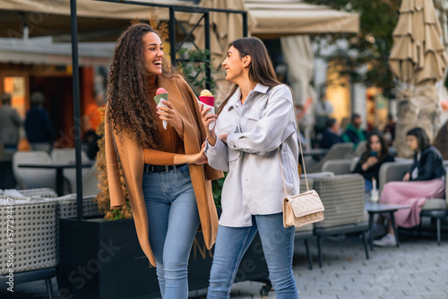 Two girls are strolling, talking and eating cone ice cream, and having much fun in the town. © DusanJelicic