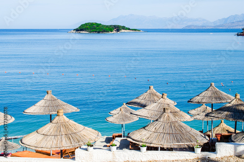 Beach with straw umbrellas and panorama of island stock photo