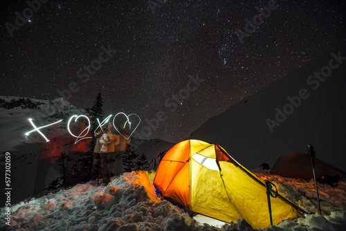 A young couple spell out XOX followed by a heart with their headlamps while camping in British Columbia, Canada. photo