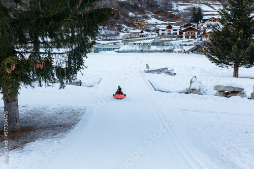 wide angle view of group of children riding one wooden sled going down snow slope