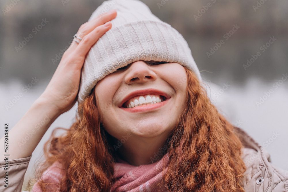 Curly redhead woman 30-35 with a cap over her eyes laughs Curly redhead woman 30-35 with a cap over her eyes laughs