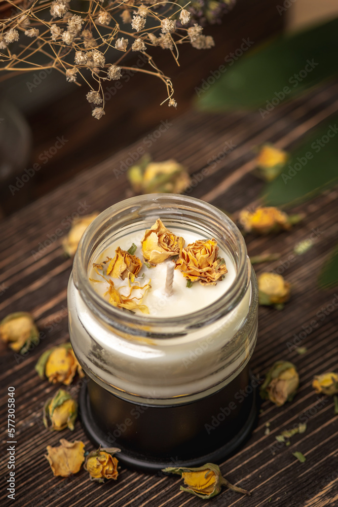 Beautiful handmade fragrant candle with yellow flower buds in a glass jar on the wooden background Beautiful handmade fragrant candle with yellow flower buds in a glass jar on the wooden background