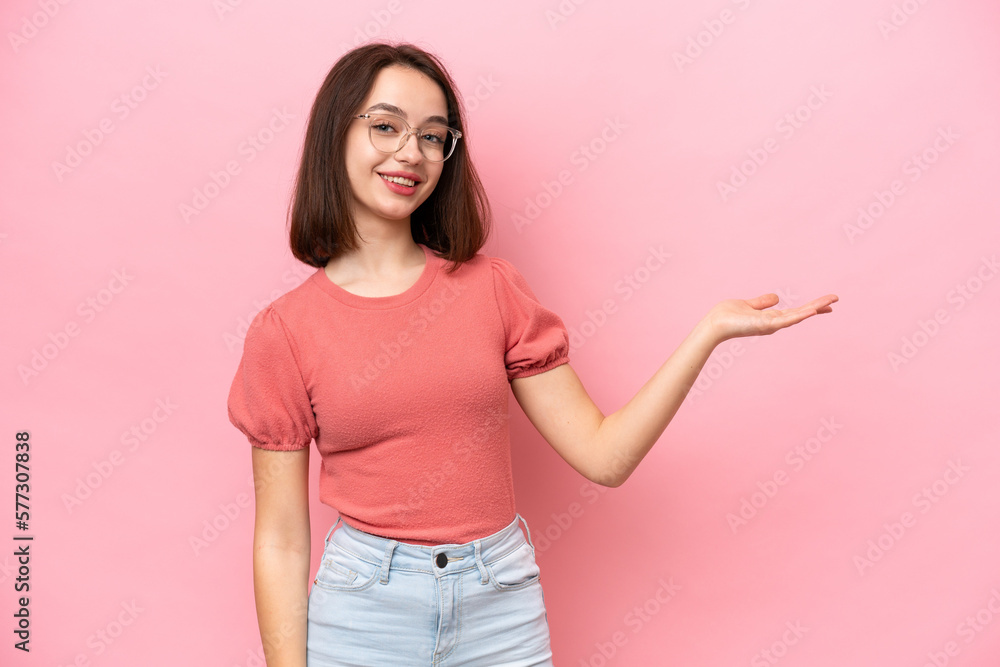 Young Ukrainian woman isolated on pink background extending hands to the side for inviting to come Young Ukrainian woman isolated on pink background extending hands to the side for inviting to come