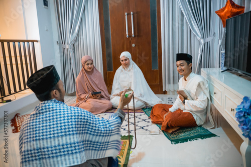 recitation leader called kyai chats with recitation participants while reciting the Quran at home photo