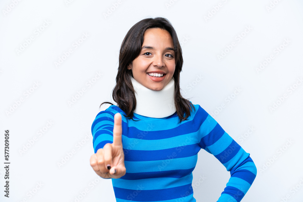 Young hispanic woman wearing neck brace isolated on white background showing and lifting a finger