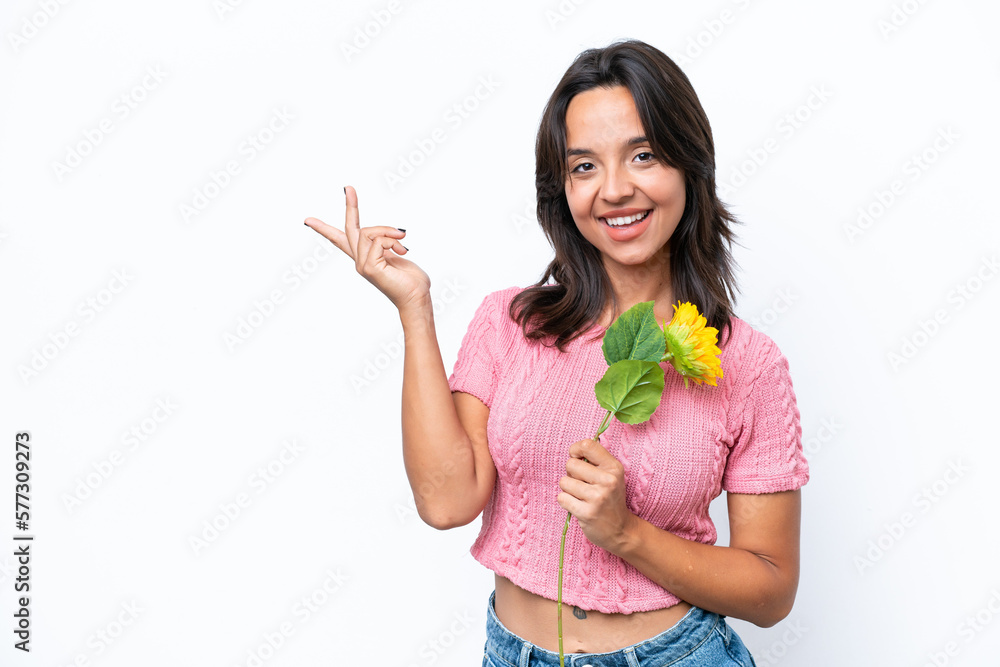 Young hispanic woman holding sunflower isolated on white background extending hands to the side for inviting to come Young hispanic woman holding sunflower isolated on white background extending hands to the side for inviting to come