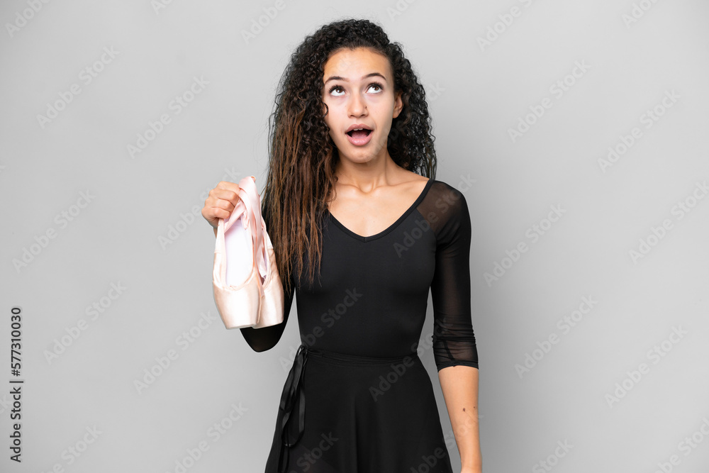 Young Arab woman dancing ballet isolated on grey background looking up and with surprised expression Young Arab woman dancing ballet isolated on grey background looking up and with surprised expression