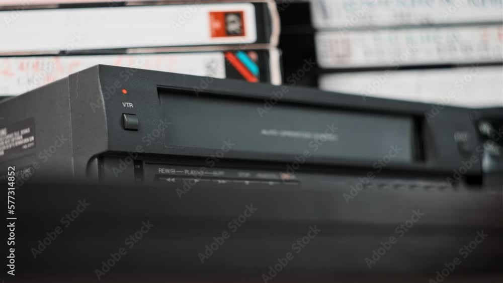 Eject VHS tape cassette from VCR player. Male hand pulls out VHS from a