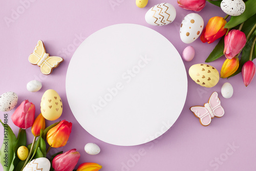 Fototapeta Naklejka Na Ścianę i Meble -  Easter celebration concept. Top view composition of white circle colorful easter eggs gingerbread and pink tulips flowers on isolated lilac background with blank space in the middle