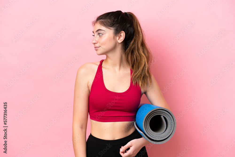 Young sport woman going to yoga classes while holding a mat looking to the side Young sport woman going to yoga classes while holding a mat looking to the side