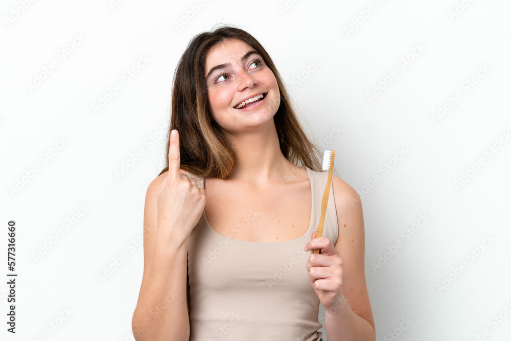 Young caucasian woman brushing teeth isolated on white background intending to realizes the solution while lifting a finger up Young caucasian woman brushing teeth isolated on white background intending to realizes the solution while lifting a finger up