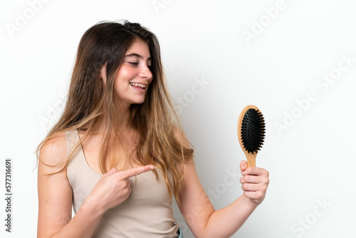 Young woman with hair comb isolated on white background pointing to the side to present a product