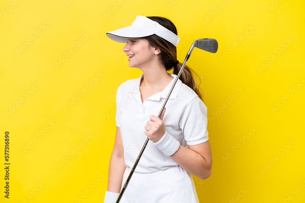 young caucasian woman playing golf isolated on yellow background laughing in lateral position young caucasian woman playing golf isolated on yellow background laughing in lateral position