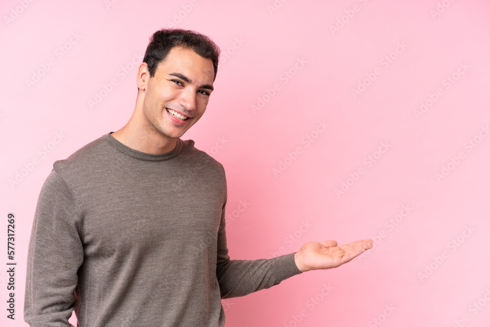 Young caucasian man isolated on pink background presenting an idea while looking smiling towards Young caucasian man isolated on pink background presenting an idea while looking smiling towards