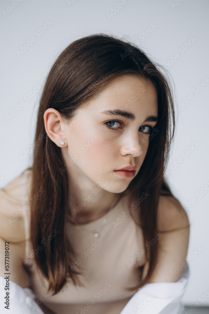 stylish portrait of a young 15-year-old model girl with natural light in a spacious photo studio