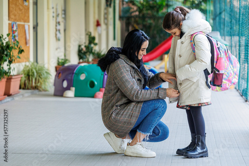 Una Madre accompagna la propria figlia a scuola e le da le raccomandazioni prima di entrare sistemandole il giubbotto