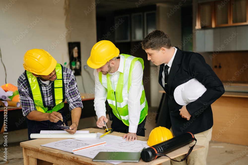 Contractor and architect looking at plan, tablet, laptop and talking about working on big project. Building in construction process. Contractor and architect looking at plan, tablet, laptop and talking about working on big project. Building in construction process.