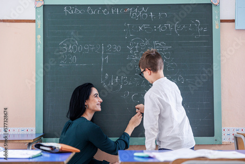 Maestra aiuta fare delle operazioni matematiche  un bambino alla lavagna di una scuola  photo