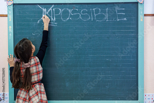 Studentessa cancella con un gesso la parola "impossible" scritta su una lavagna