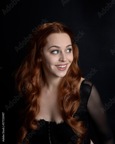 close up portrait of beautiful woman with long red hair wearing sheer corset top. variety of facial expressions, Isolated on dark studio background with moody silhouette lighting.