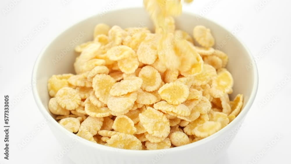 Corn flakes pour in bowl, close up. Perfect traditional breakfast Corn flakes pour in bowl, close up. Perfect traditional breakfast