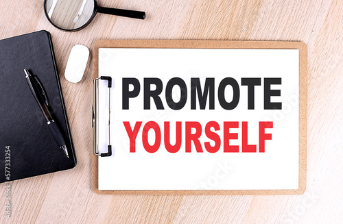 PROMOTE YOURSELF text on clipboard on wooden background © Iryna
