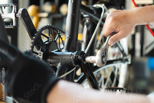 Technician makes adjustments to Crankset on a folding bicycle working in workshop , Bicycle Repair and maintenance concept