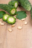 Closeup of fresh bitter gourd with cut slice isolated on wooden background.