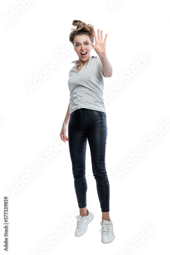 Joyful young woman is jumping. Beautiful blonde in black leggings, a gray t-shirt and white sneakers. Positivity and happiness. Full height. Isolated on white background. Vertical.