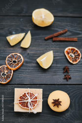 Handmade soap bars and citrus fruit on dark table top view. Piece of handmade lemon soap and fresh lemons