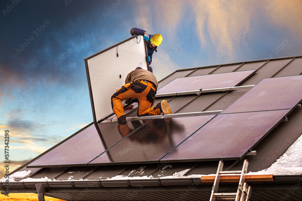 Naklejka premium Workers assemble photovoltaic panels on the roof of the building