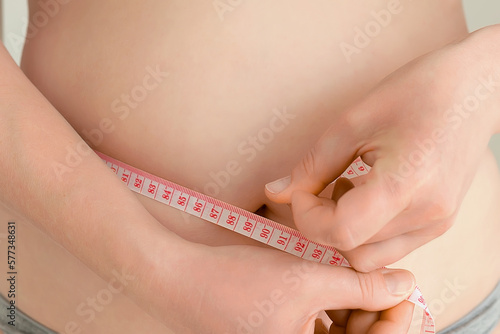 The girl taking measurements of her body. woman measuring her waist with a measuring tape. Reduction of overweight and obesity treatment. Healthy lifestyle.