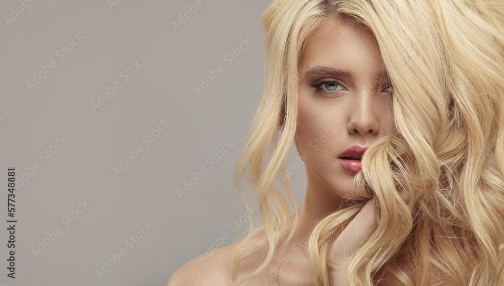 Much attractive blonde woman with long healthy curly hair on beige isolated with free copy space