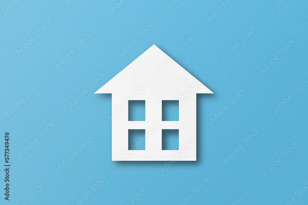 White paper cut out house shape isolated on light blue paper background.
