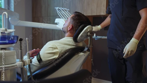 Man dentist preparing patient for the procedure in light dental clinic. Hydience and healthy photo