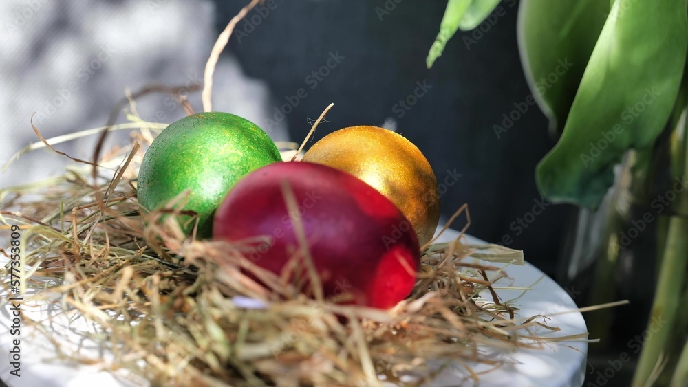 Easter colorful eggs rotate in nest with hey outdoor in sunny warming day.