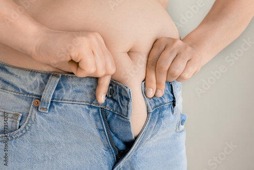 Fat woman trying to wear jeans. belly in jeans. Concept of excessive weight, obese female, dieting and overweight problems.