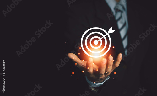 Businessman holding virtual dart board and arrows with copy space for setting business targets