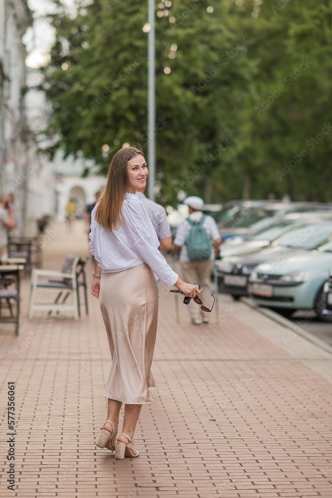 a happy beautiful girl walks around the city in the summer, a girl in a non-Russian image at sunset, a vertical frame, freedom