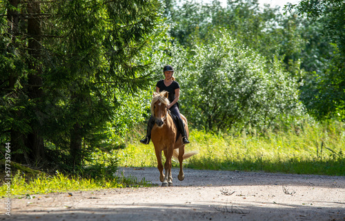 Woman horseback riding in forest trail © citikka