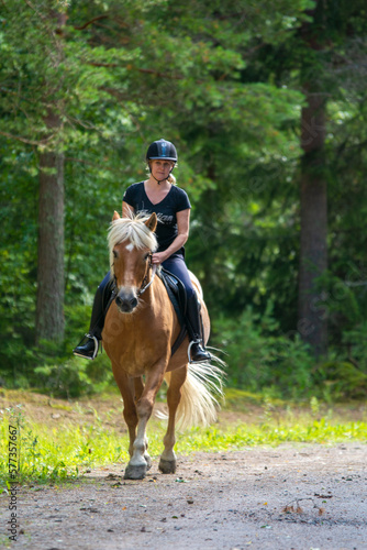 Woman horseback riding in forest trail