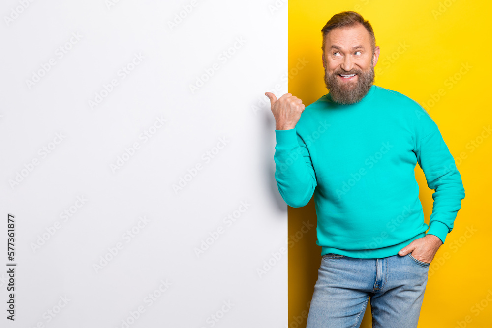 Photo portrait of handsome granddad point empty space white wall excited dressed stylish cyan look isolated on yellow color background Photo portrait of handsome granddad point empty space white wall excited dressed stylish cyan look isolated on yellow color background