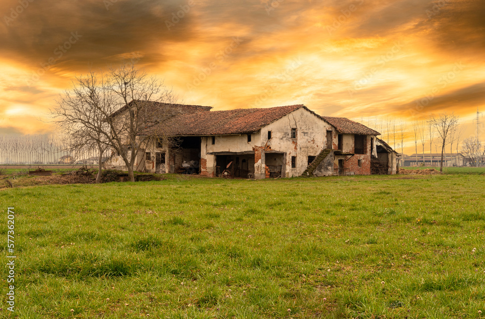 Old abandoned farmhouse with typical rural architecture of the Po Valley in the province of Cuneo, Italy, at sunset with colorated cloudy sky Old abandoned farmhouse with typical rural architecture of the Po Valley in the province of Cuneo, Italy, at sunset with colorated cloudy sky