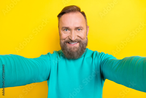 Photo portrait of attractive grandpa take selfie front camera cheerful wear trendy aquamarine outfit isolated on yellow color background