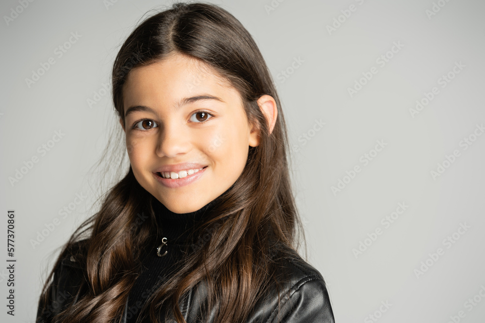 Portrait of brunette kid in leather jacket looking at camera isolated on grey. Portrait of brunette kid in leather jacket looking at camera isolated on grey.