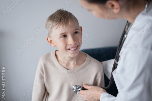 Doctor and happy smiling child boy patient at home medical inspection. Medicine, healthcare concepts.