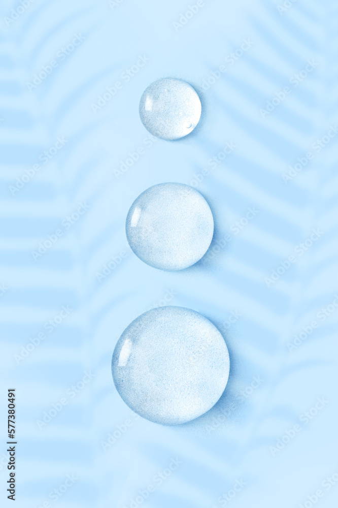 round drops of transparent gel serum on blue background round drops of transparent gel serum on blue background