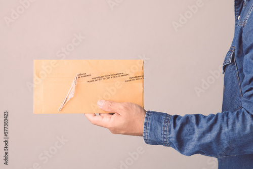 Man holding brown confidential envelope sealed with tape and word Please do not accept if seal is broken in Thai and English. photo