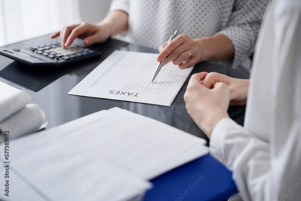 Woman accountant using a calculator and laptop computer while counting taxes for a client. Business audit and finance concepts. Woman accountant using a calculator and laptop computer while counting taxes for a client. Business audit and finance concepts.